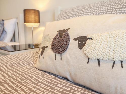 two sheep on a pillow on a bed at Harbour View in Porthmadog