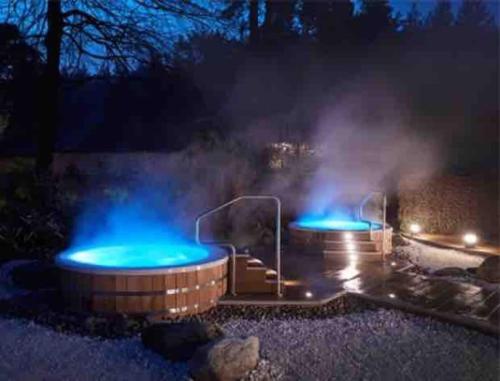 2 bañeras de hidromasaje con luces azules en un patio por la noche en Large historic family home nr Longleat and Bath, en Warminster