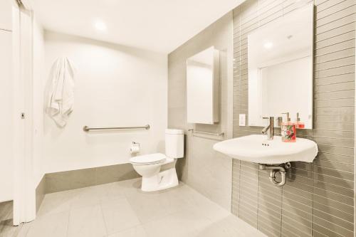 a white bathroom with a toilet and a sink at Urban Chic: Sleek 2BR in Heart of Vancouver in Vancouver