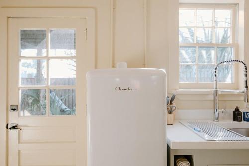 a white refrigerator in a kitchen next to a window at The Bungalow Lounge by WB Abodes in Wrightsville Beach