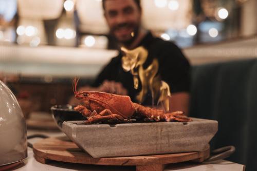 a man is standing next to a plate of lobster at Hyatt Zilara Cap Cana - Adults Only in Punta Cana