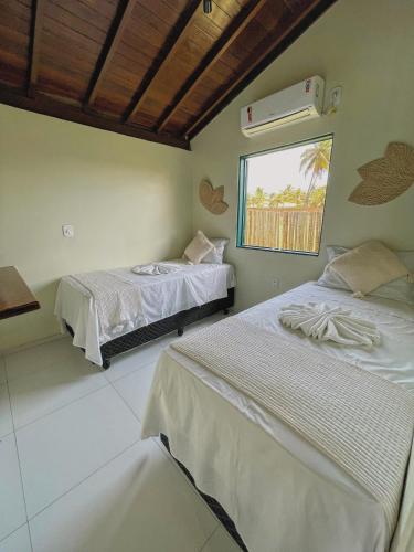 a bedroom with two beds and a window at Pousada Paradise in Coruripe