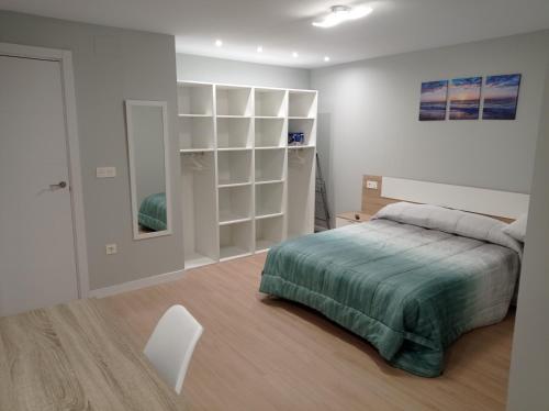 a white bedroom with a bed and a white chair at A orillas del Duero in Soria