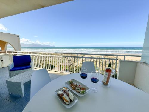 a table with a plate of food and two glasses of wine at La perla sulla spiaggia in Alcamo Marina