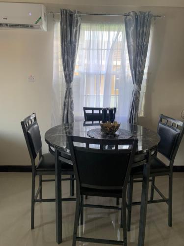 a dining room table with black chairs and a window at MJ Manor in Old Harbour