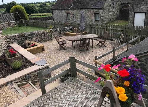a garden with a wooden bench and a table and flowers at The Old Coop Barn in Brassington