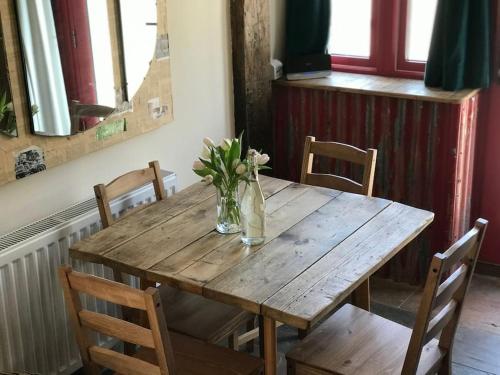 a wooden table with chairs and a vase of flowers on it at The Old Coop Barn in Brassington