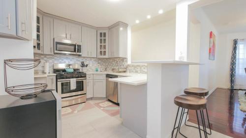 a kitchen with white cabinets and a stove top oven at Escape to Raleigh Ave - Steps from the Beach in Atlantic City