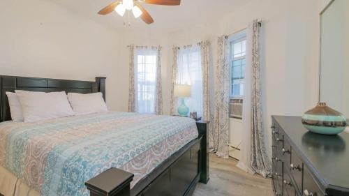 a bedroom with a bed and a dresser and windows at Escape to Raleigh Ave - Steps from the Beach in Atlantic City