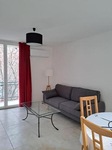 un salon avec un canapé et une table en verre dans l'établissement Grand T2 Clim & Fibre - centre universités Béziers, à Béziers