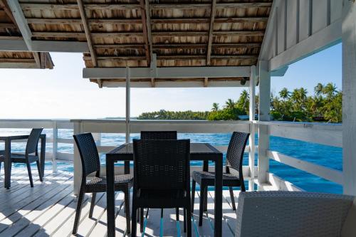 - une table et des chaises sur une terrasse donnant sur l'océan dans l'établissement Motu Fara Private Island, à Avatoru