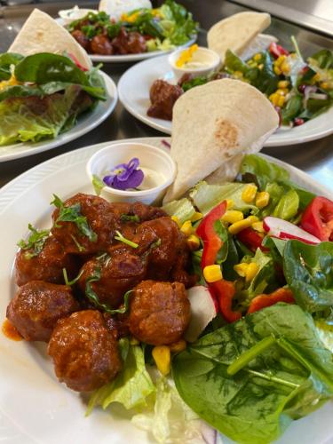 a plate of food with meat and salad on a table at Bed and Brunsj, Sand in Sand