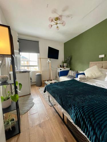 1 dormitorio con cama y pared verde en Fulham studio flat en Londres