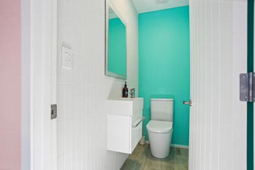 a bathroom with a white toilet and a blue wall at Waihi Wonder - Waihi Holiday Home in Waihi Beach