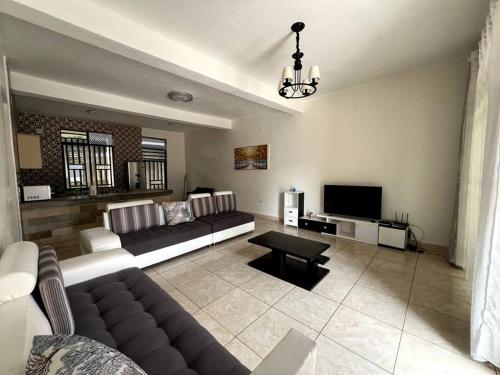 a living room with a couch and a television at Alma Residence Apartment in Rubavu