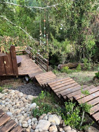 a wooden bridge with a bench and some rocks at Wincarayen Lodge & Cabañas in Panguipulli