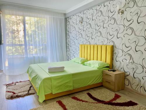 um quarto com uma cama com uma cabeceira amarela e uma parede em Apartament comfort Centru em Chisinau