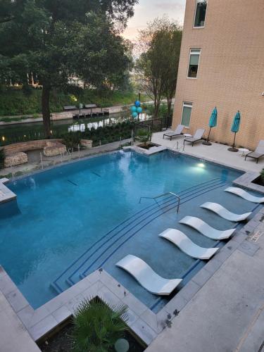 a large swimming pool with lounge chairs in front of a building at Downtown Apartment with Riverwalk views Free Parking Pet Friendly Centrally Located on the Riverwalk in San Antonio