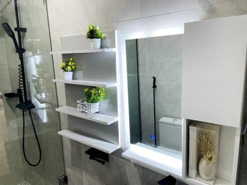 a bathroom with white shelves and a shower with a mirror at WHITEFIELD LUXURY APARTMENT in Orimedu