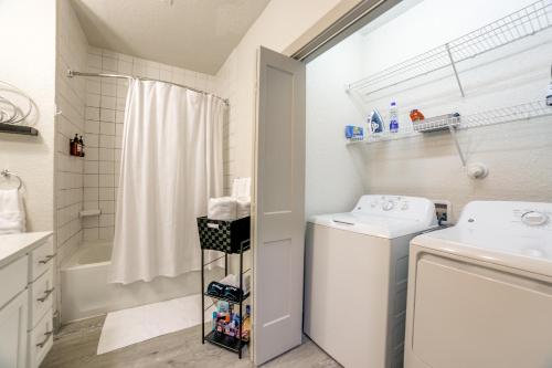 een badkamer met een wastafel, een wasmachine en een droger bij Downtown Apartment with Riverwalk views Free Parking Pet Friendly Centrally Located on the Riverwalk in San Antonio