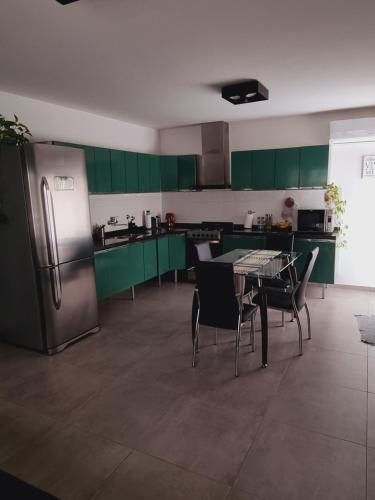 eine Küche mit grünen Schränken und einem Kühlschrank aus Edelstahl in der Unterkunft Habitación Córdoba Capital centro cerca de todo in Cordoba