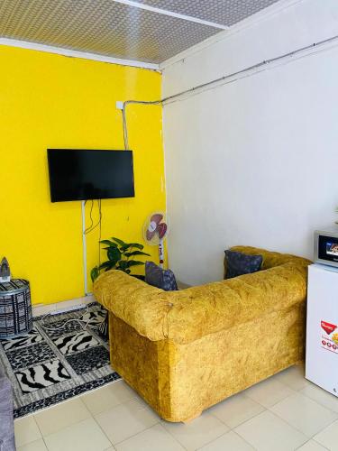 uma sala de estar amarela com um sofá e uma televisão em Serenity Studio Nakuru CBD-WiFi-Ample Parking-Netflix-Budget Rates em Nakuru