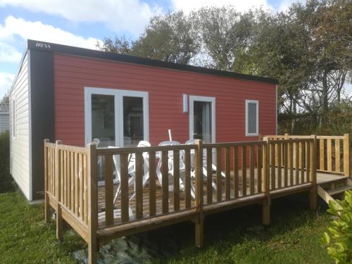 a red and black tiny house with a wooden deck at Camping de Lanven in Plomeur