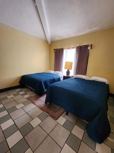 2 Betten in einem Zimmer mit blauer Bettwäsche in der Unterkunft Las Flores in San Pedro Carchá