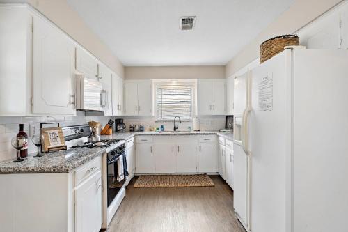 a white kitchen with white cabinets and a refrigerator at with Arcade and Covered Patio Sleep 9 in this 4 Bedroom 2 Bath Home 5 star host Deer Park TX in Deer Park