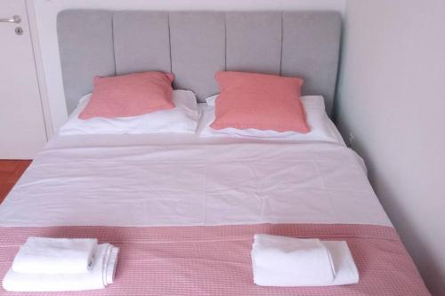 a white bed with two pink pillows on it at City Pag Apartment in Pag
