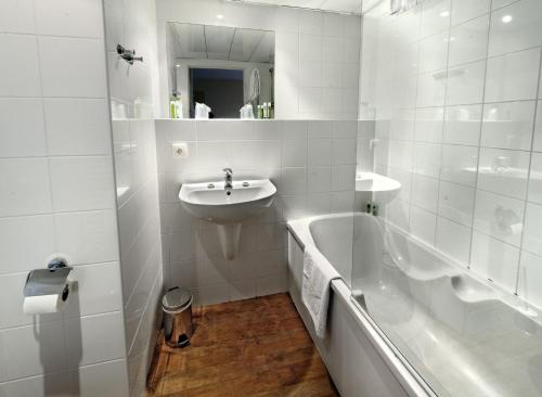 a white bathroom with a sink and a bath tub at Odalys City Antibes Olympe in Antibes