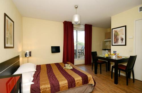 ein Hotelzimmer mit einem Bett und einem Tisch in der Unterkunft Odalys City Antibes Olympe in Antibes