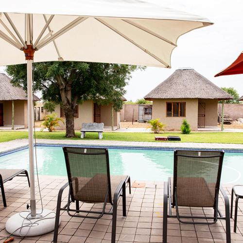a table and chairs with an umbrella next to a pool at In The Bush Farm Lodge in Winterveld