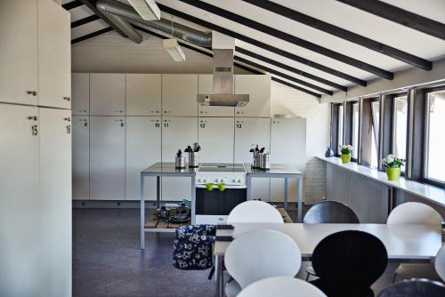 a kitchen with white cabinets and white tables and chairs at STAY and SLEEP Grindsted - Billund in Grindsted