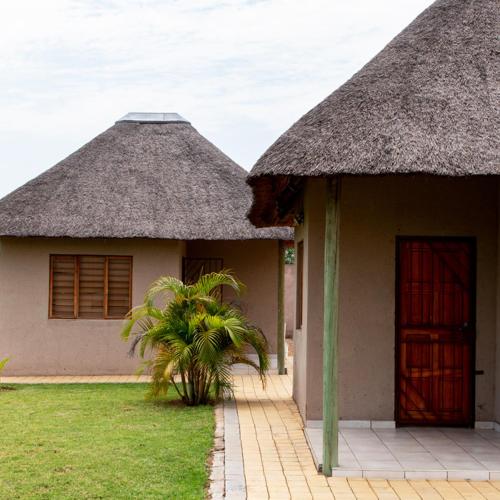 a small house with a thatched roof and a door at In The Bush Farm Lodge in Winterveld