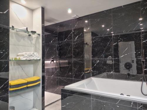 a bathroom with a tub and a black tiled wall at Boutique Apartment Owned by Emperor Peter The Great With 2 Balconies & Jacuzzi in Karlovy Vary