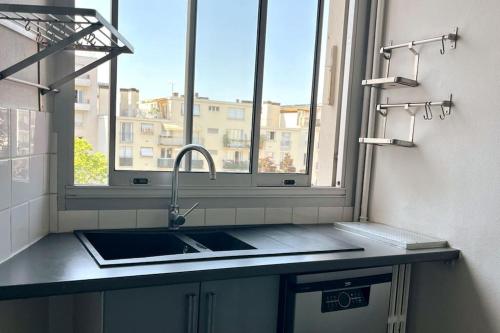 a kitchen counter with a sink and a window at 2P calme - climatisation - 70m du métro M4 Barbara - 4 pers maximum in Montrouge