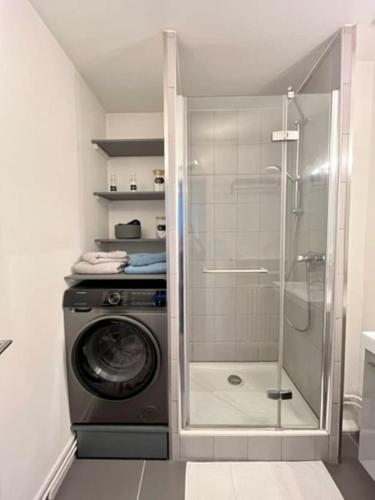 a bathroom with a shower and a washing machine at 2P calme - climatisation - 70m du métro M4 Barbara - 4 pers maximum in Montrouge
