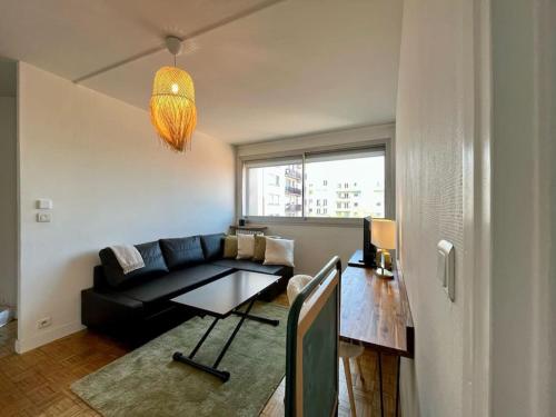 a living room with a black couch and a table at 2P calme - climatisation - 70m du métro M4 Barbara - 4 pers maximum in Montrouge