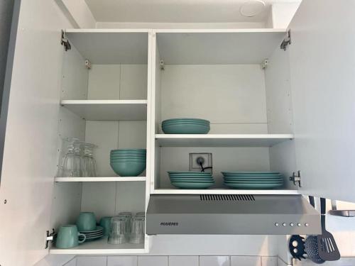 a kitchen with white shelves with blue dishes on them at 2P calme - climatisation - 70m du métro M4 Barbara - 4 pers maximum in Montrouge