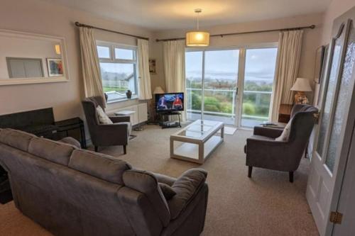 Una sala de estar con un sofá y sillas y un televisor. en Gurranebawn, Cahersiveen, en Cahersiveen