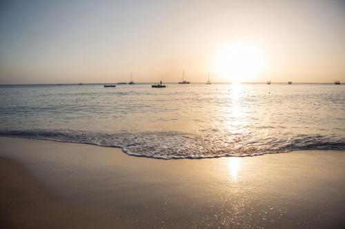 a beach with boats in the water at sunset at Colony Club, a Luxury Collection Resort, Barbados in Saint James