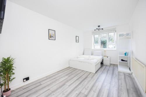 Modern 2 BR Near Brixton Station في لندن: غرفة معيشة بجدران بيضاء وأريكة بيضاء