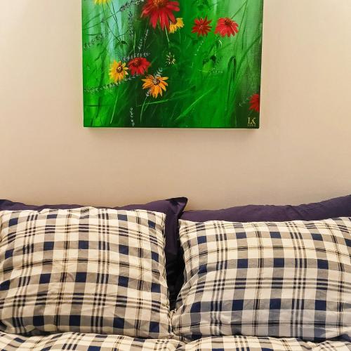obraz wiszący na ścianie nad kanapą z poduszkami w obiekcie Gniazdo w Felicjanowie w Uniejowie
