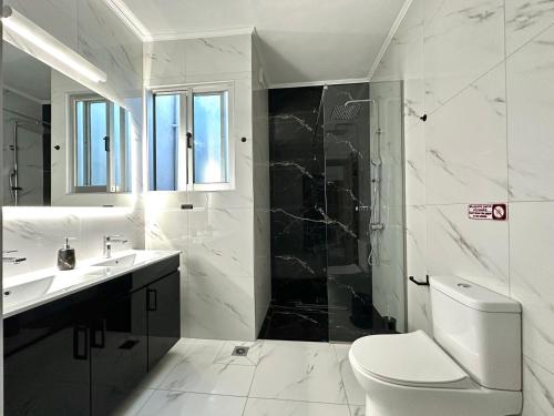 a bathroom with a toilet and a sink and a shower at W Pearl Suite in Nea Peramos