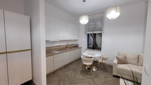 a kitchen with white cabinets and a table and chairs at Apartament Jaracza 28/7 in Słupsk