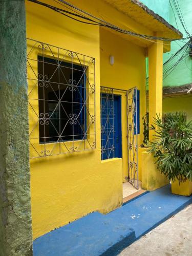 una casa amarilla con una puerta azul y una ventana en casinhavila130 en Salvador