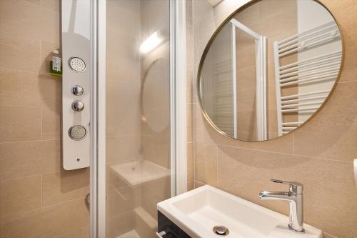 une salle de bain avec un lavabo et un miroir dans l'établissement Guestrust - Champeret Porte Maillot - Ternes, à Paris