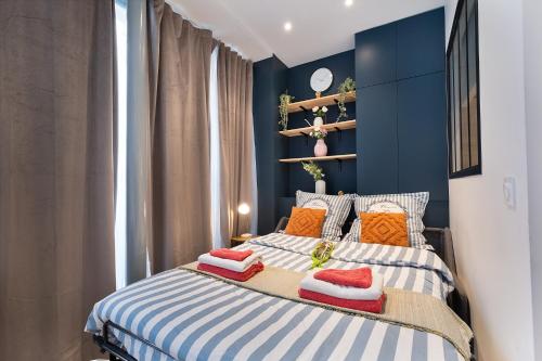a bedroom with a bed with blue walls and orange pillows at Guestrust - Champeret Porte Maillot - Ternes in Paris