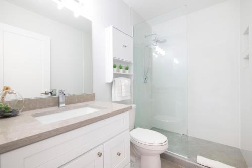a white bathroom with a toilet and a sink at Summertime Suites #49 in West Bay